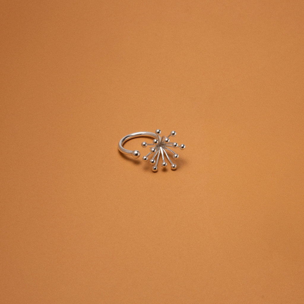 Silver ring with star-like design on an orange background