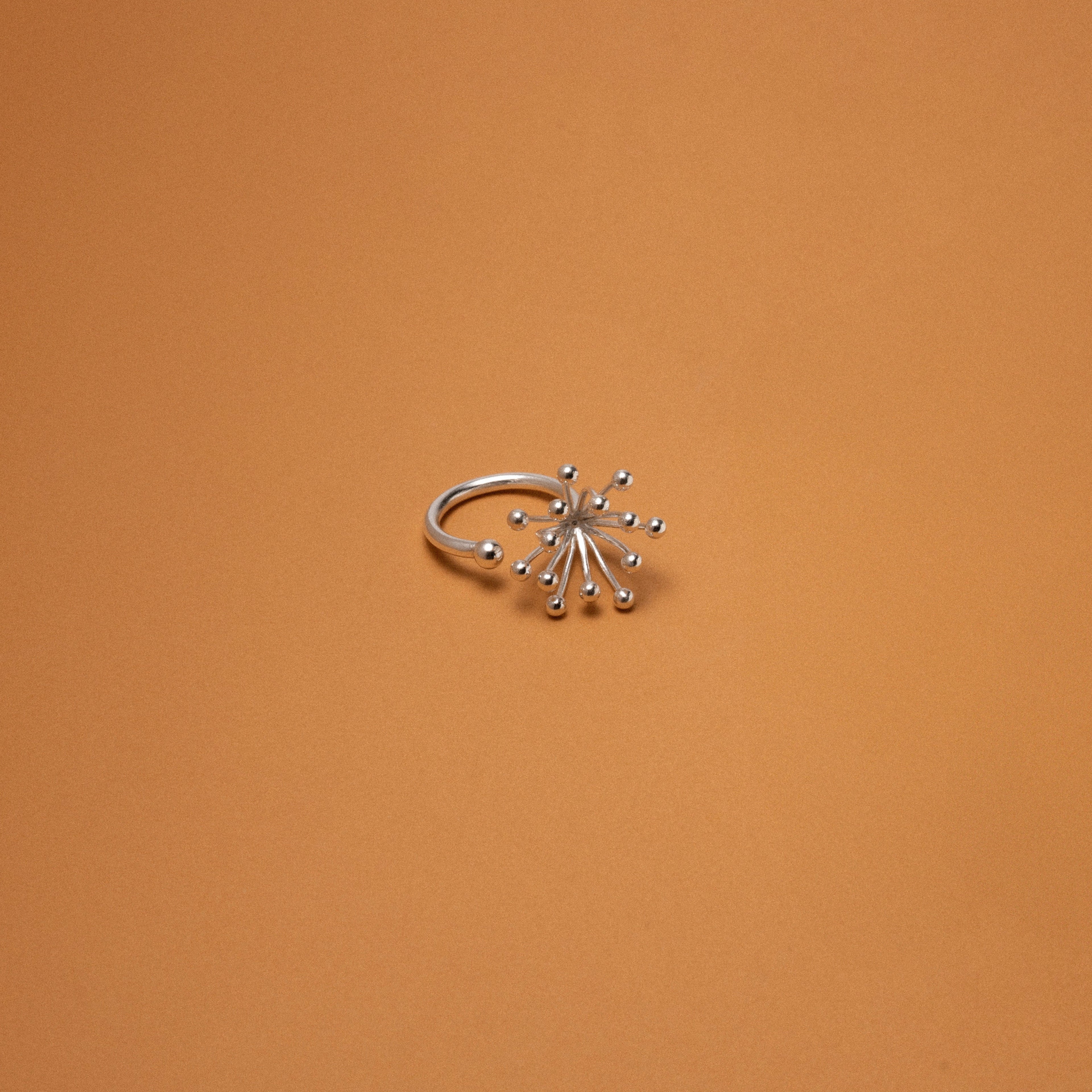 Silver ring with star-like design on an orange background