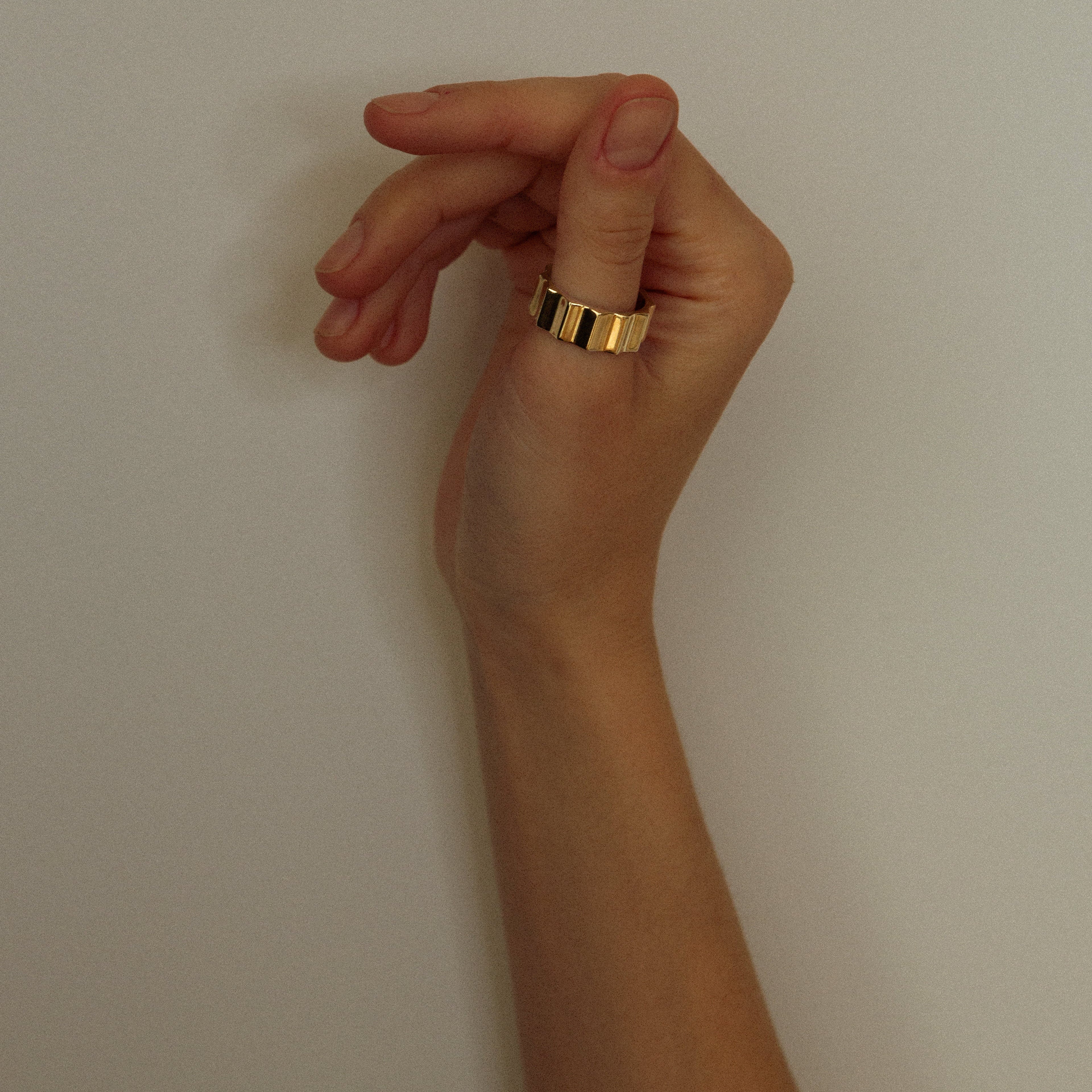 Hand with a gold ring on a plain background