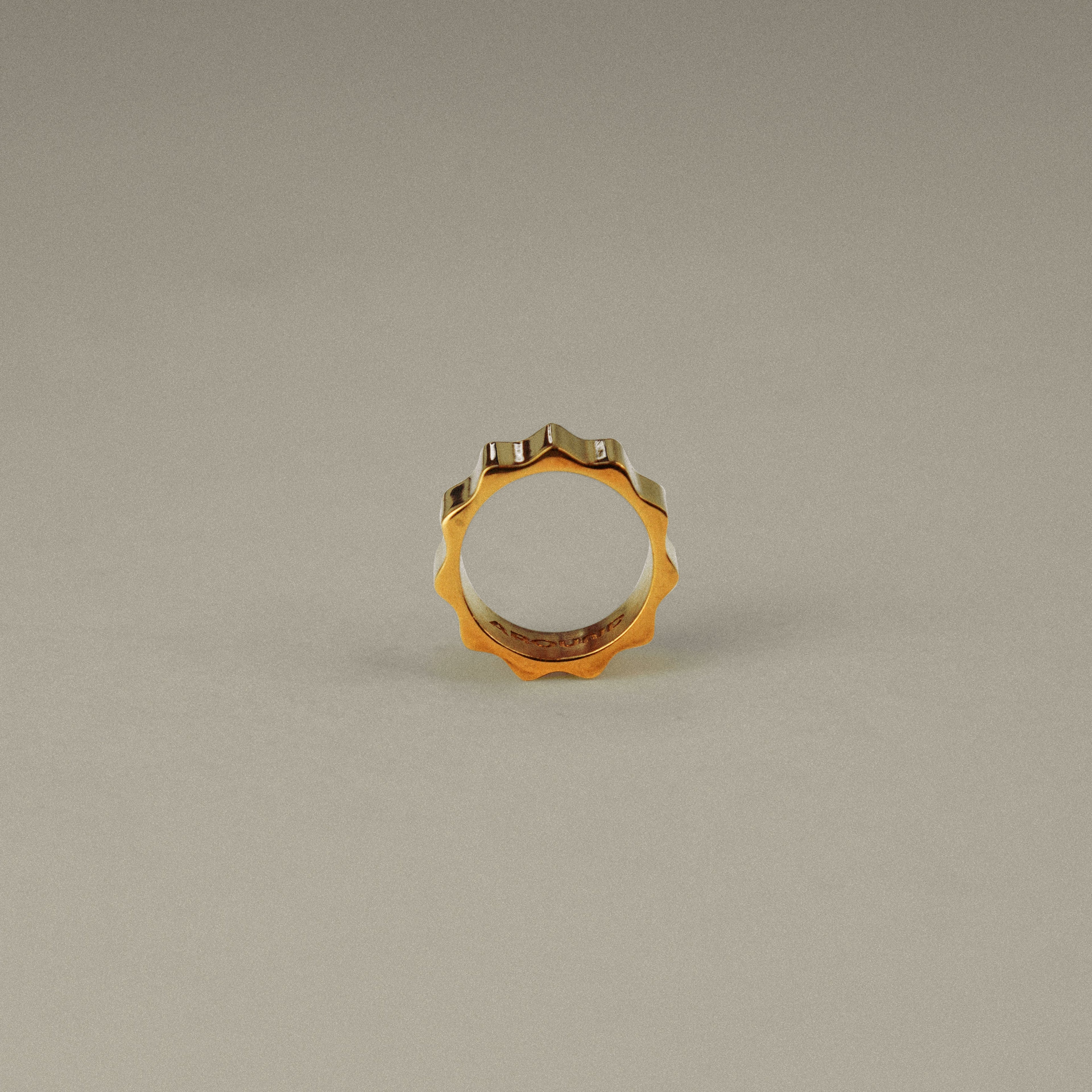 Gold ring with embedded stones on a beige background